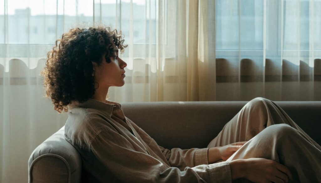 Should I Get Back With My Ex? 7 Questions to Ask First 4 A person sits quietly beside a sunlit window, taking a moment to reflect.